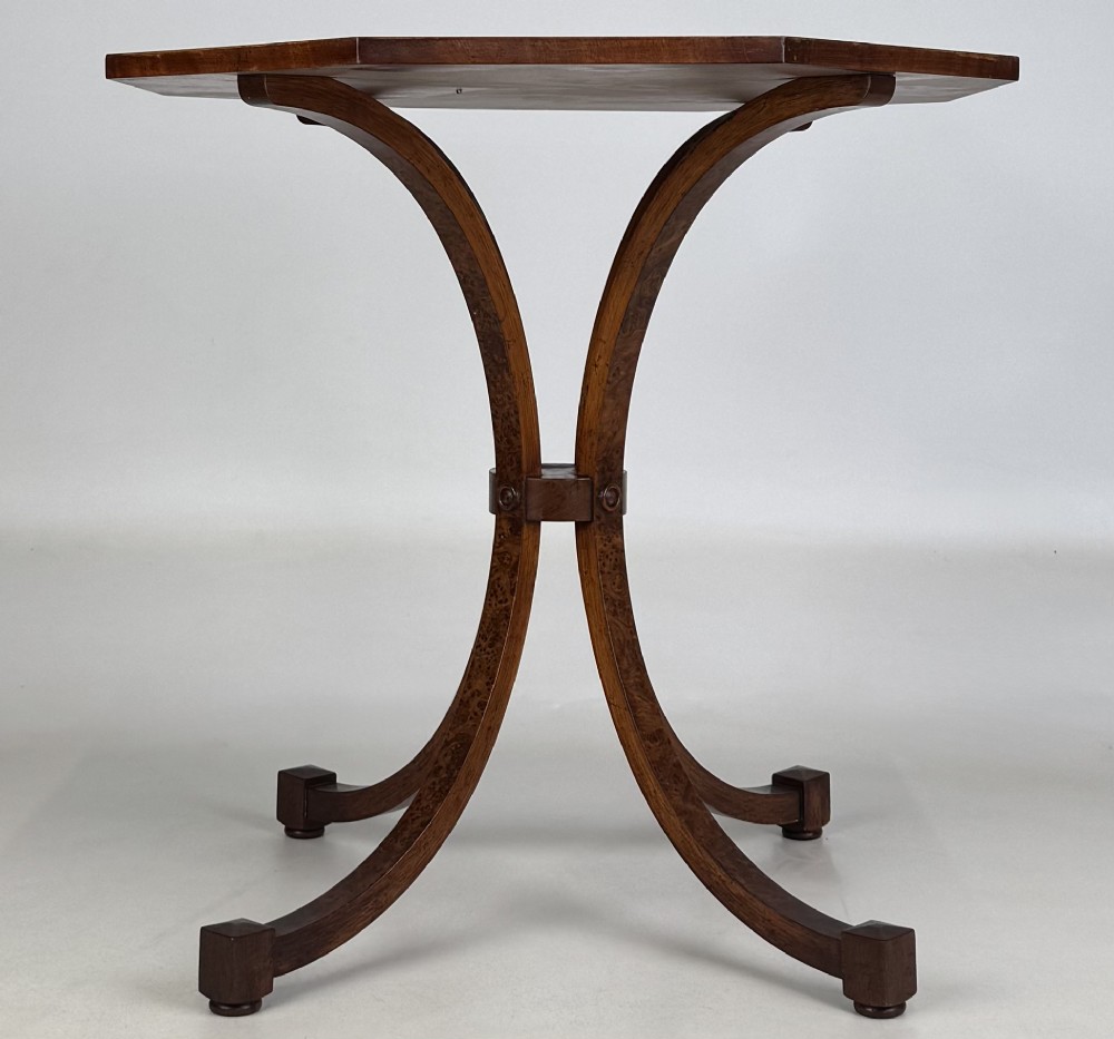 An octagonal side table crafted from burr walnut featuring four outward-curving legs joined by a central collar.