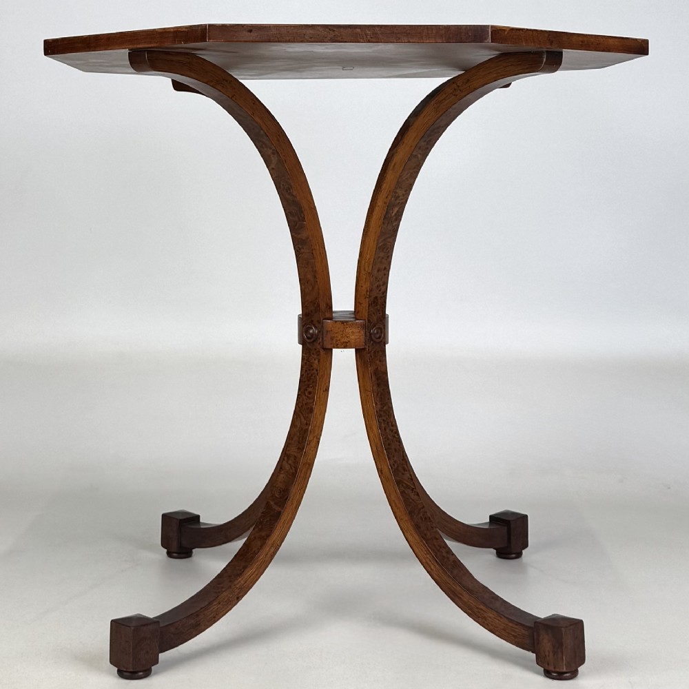 An octagonal side table crafted from burr walnut featuring four outward-curving legs joined by a central collar. View III