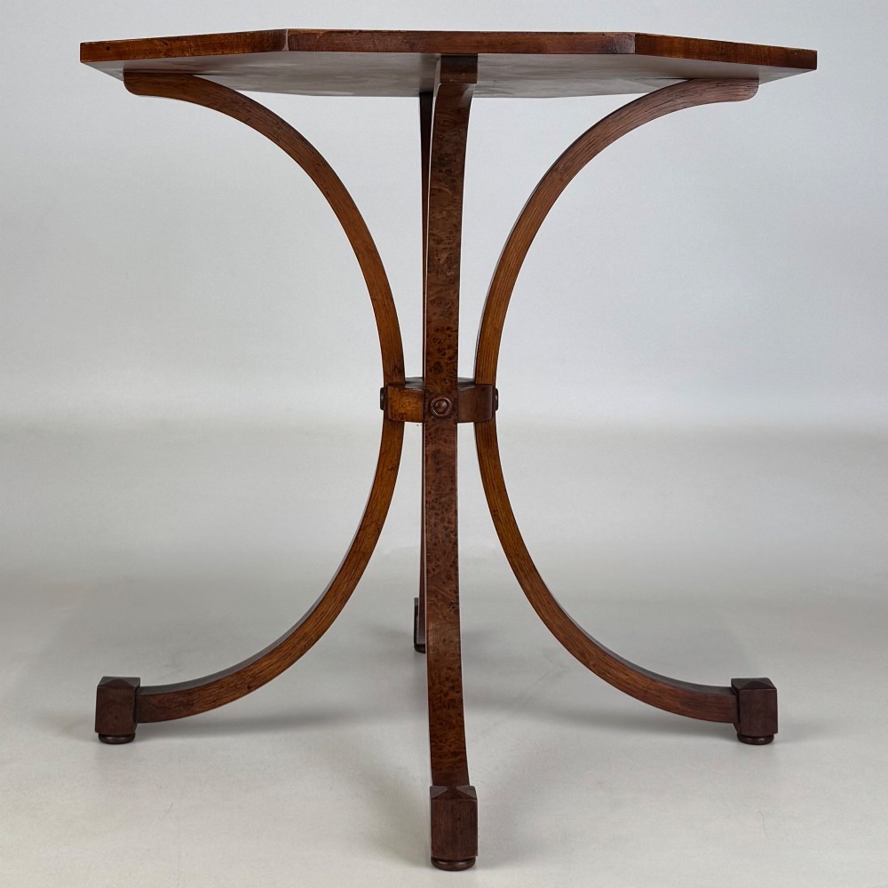 An octagonal side table crafted from burr walnut featuring four outward-curving legs joined by a central collar. View IV