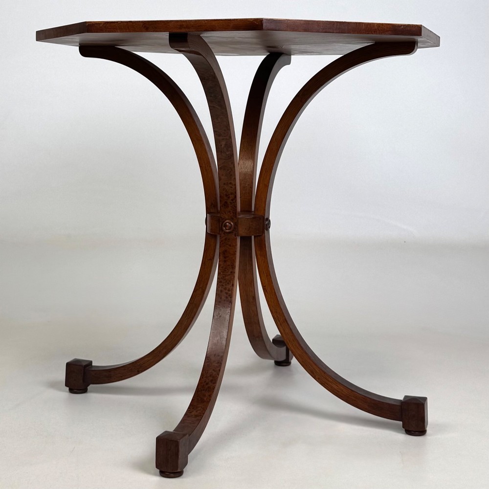 An octagonal side table crafted from burr walnut featuring four outward-curving legs joined by a central collar. View V