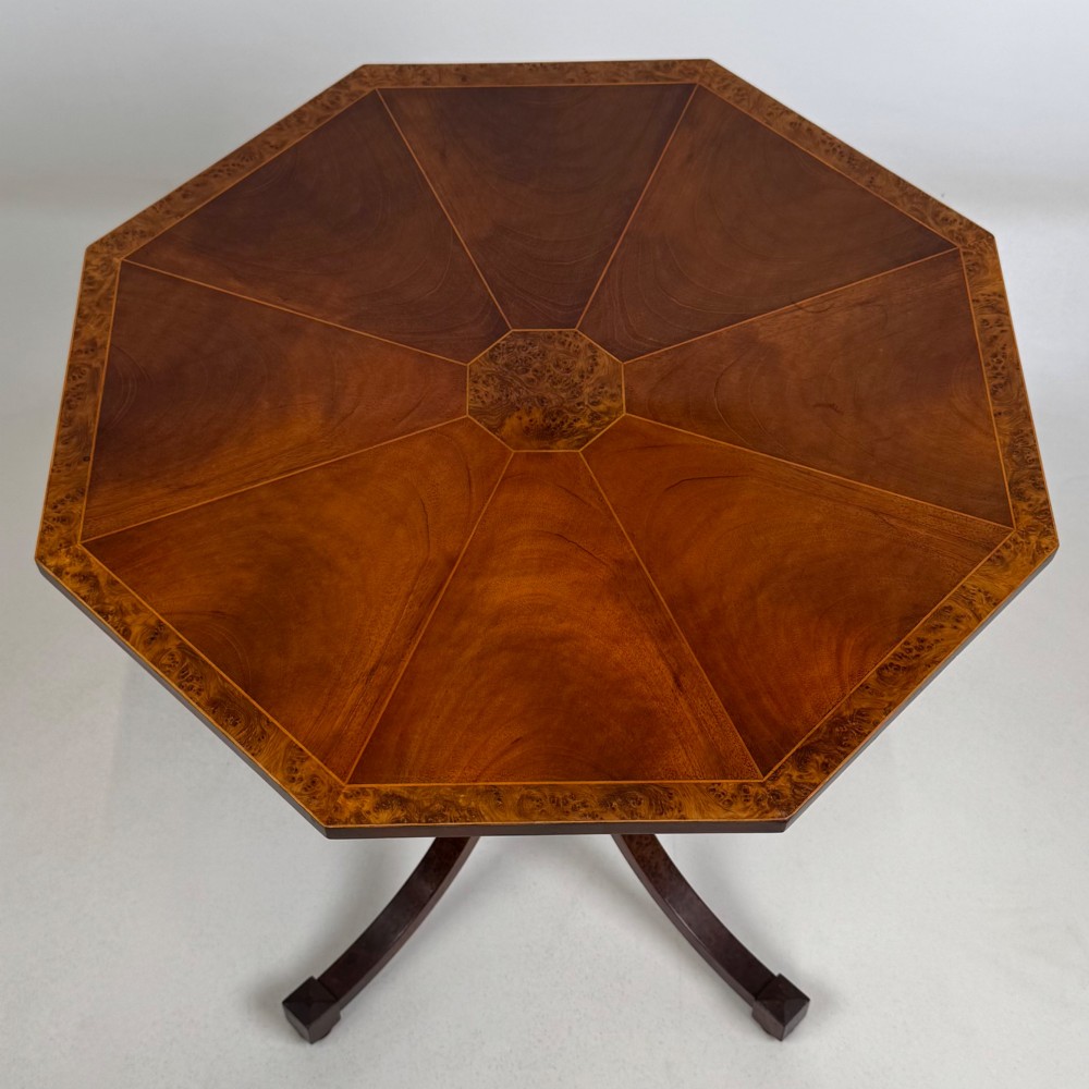 An octagonal side table crafted from burr walnut featuring four outward-curving legs joined by a central collar. View VI
