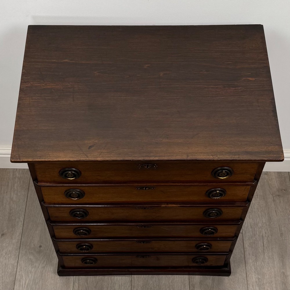 An antique Edwardian mahogany chest of drawers featuring six graduated drawers with round brass ring handles. View IX