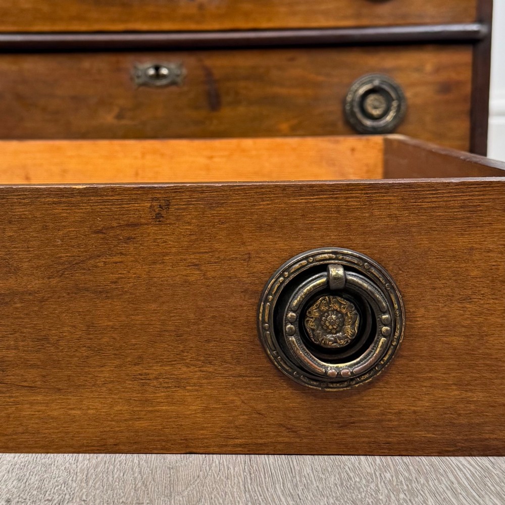 An antique Edwardian mahogany chest of drawers featuring six graduated drawers with round brass ring handles. View XI