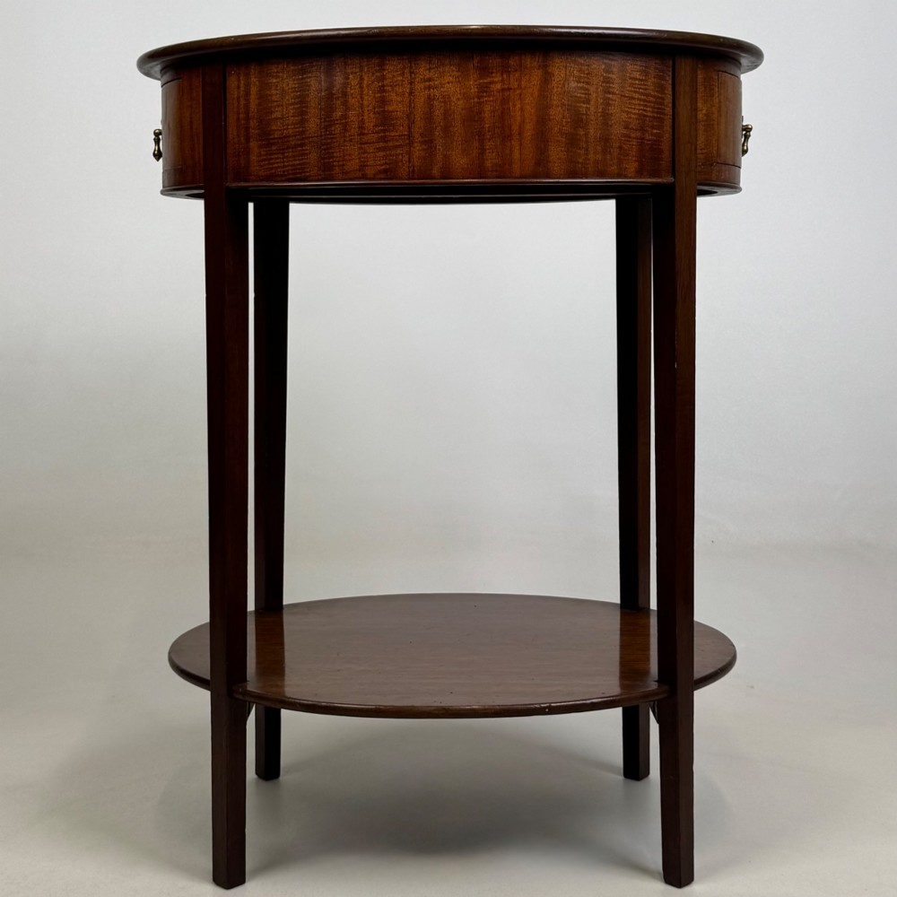 A tall Edwardian mahogany oval side table featuring a single top drawer with a brass handle and an oval lower undertier shelf. View III