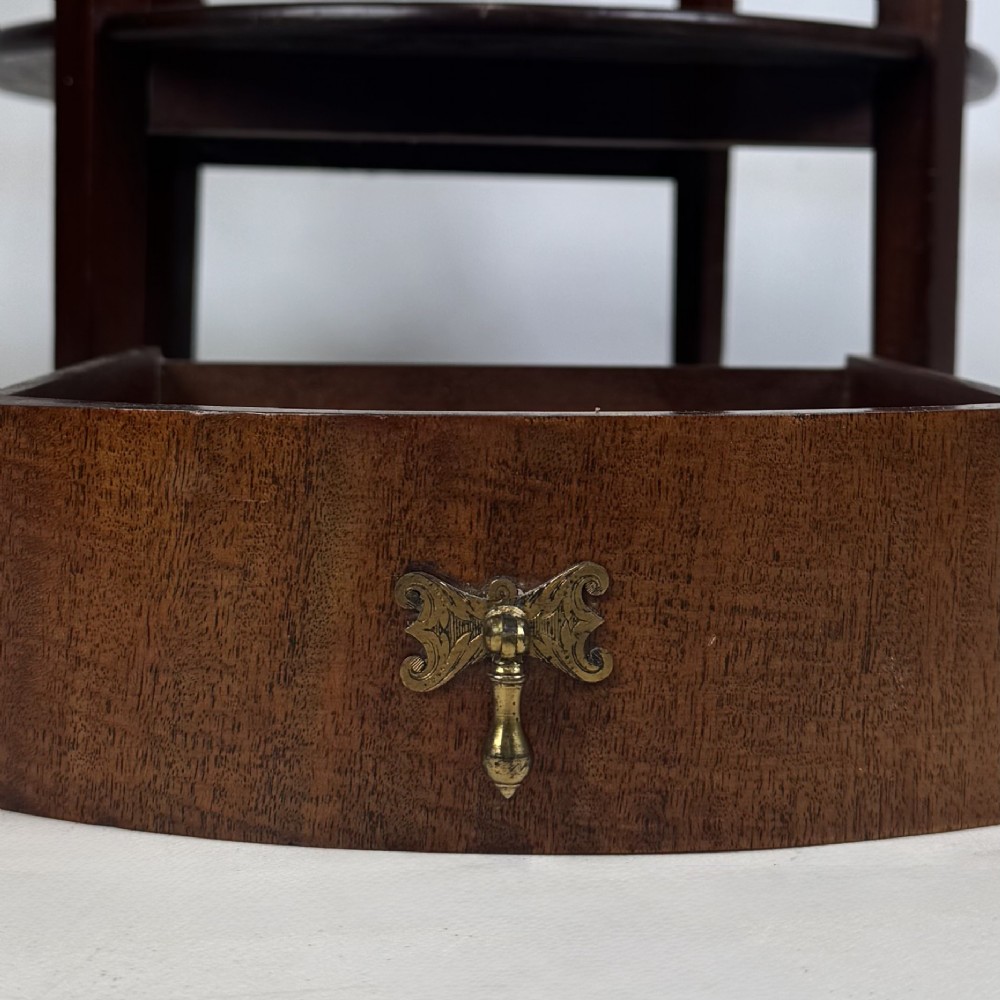 A tall Edwardian mahogany oval side table featuring a single top drawer with a brass handle and an oval lower undertier shelf. View XI