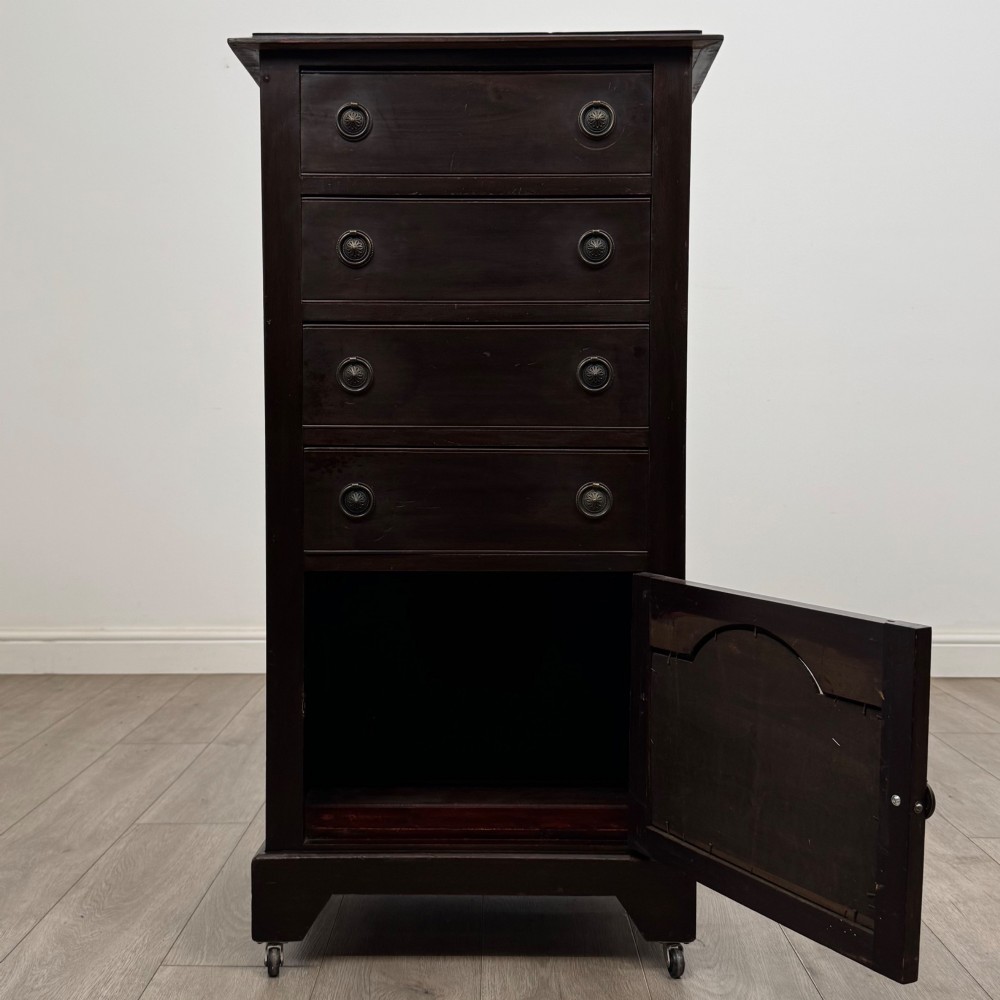 A tall, dark mahogany Edwardian chest features four stacked drawers above a single carved cupboard door, set on small brass castors. View II