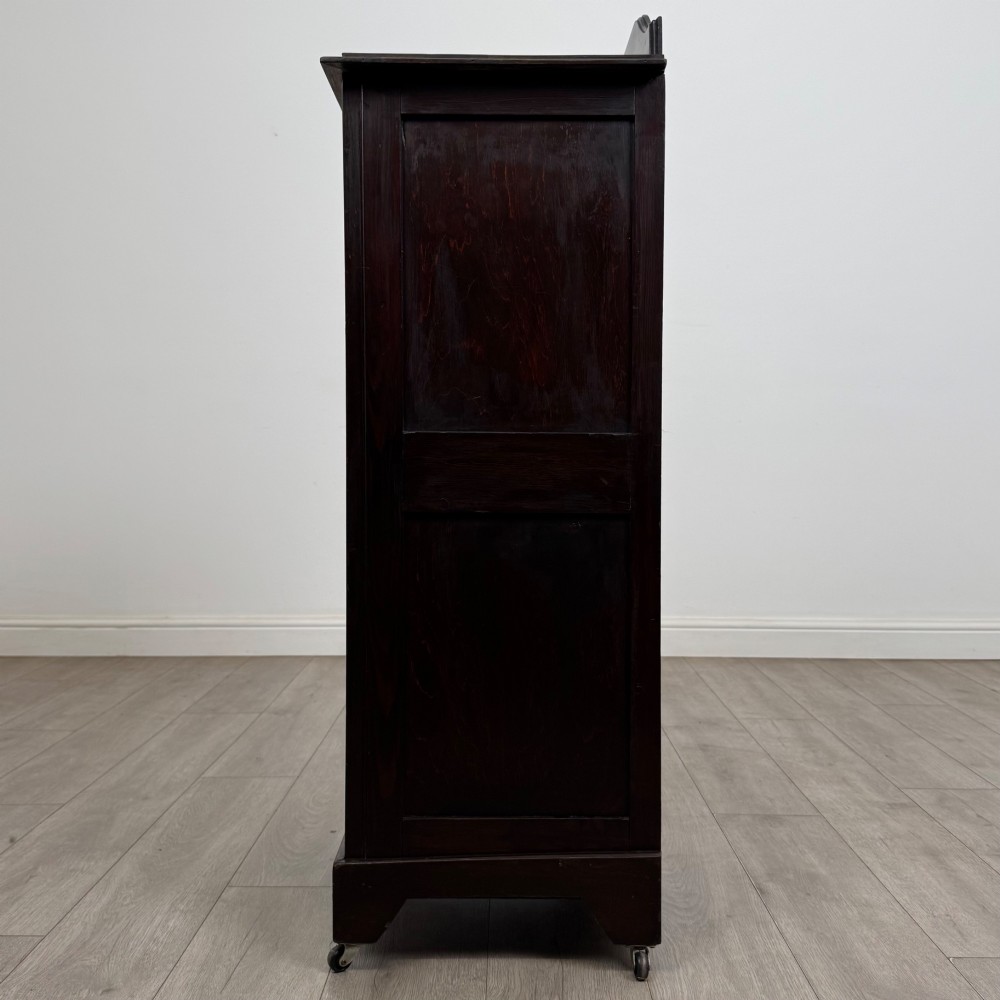 A tall, dark mahogany Edwardian chest features four stacked drawers above a single carved cupboard door, set on small brass castors. View IV