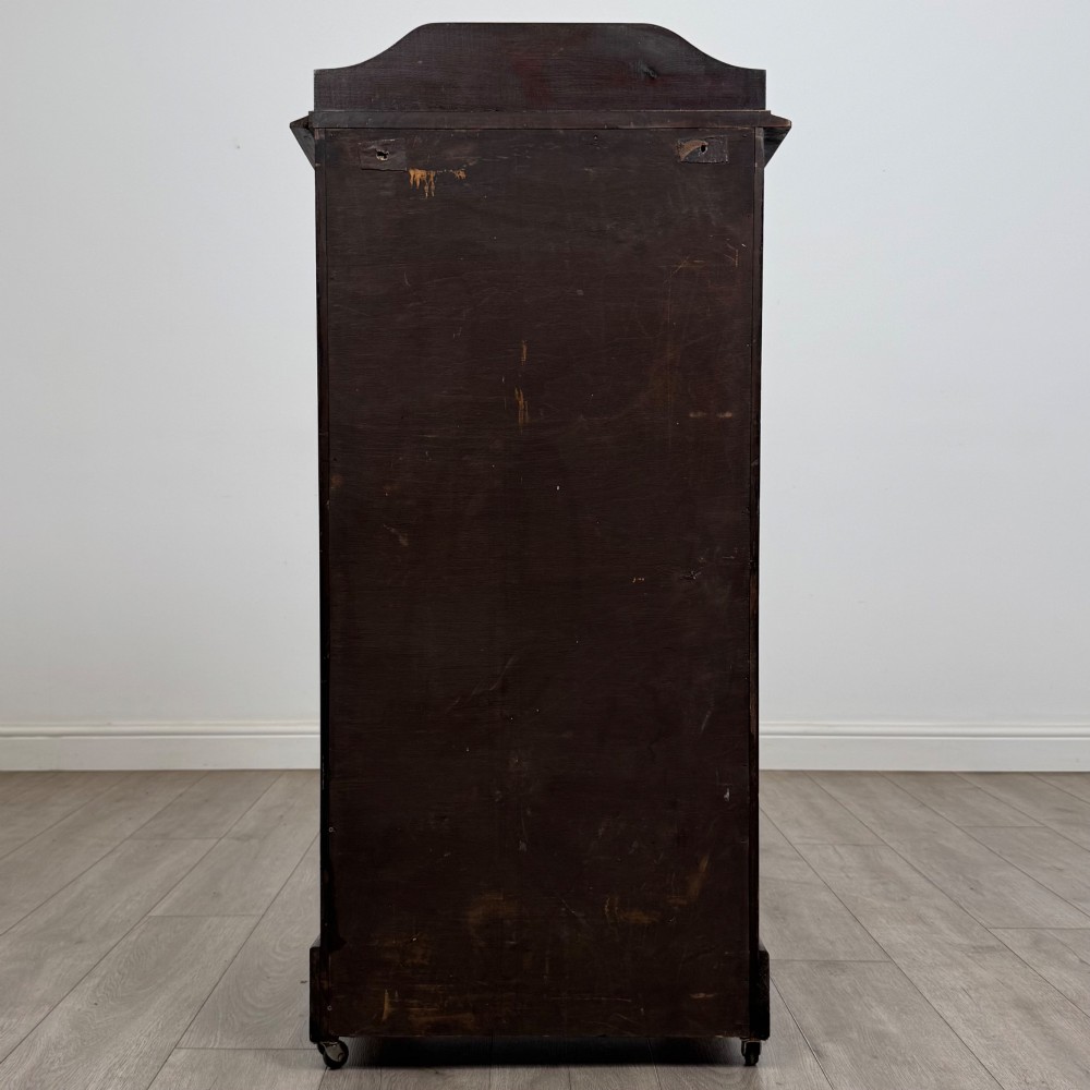 A tall, dark mahogany Edwardian chest features four stacked drawers above a single carved cupboard door, set on small brass castors. View VI