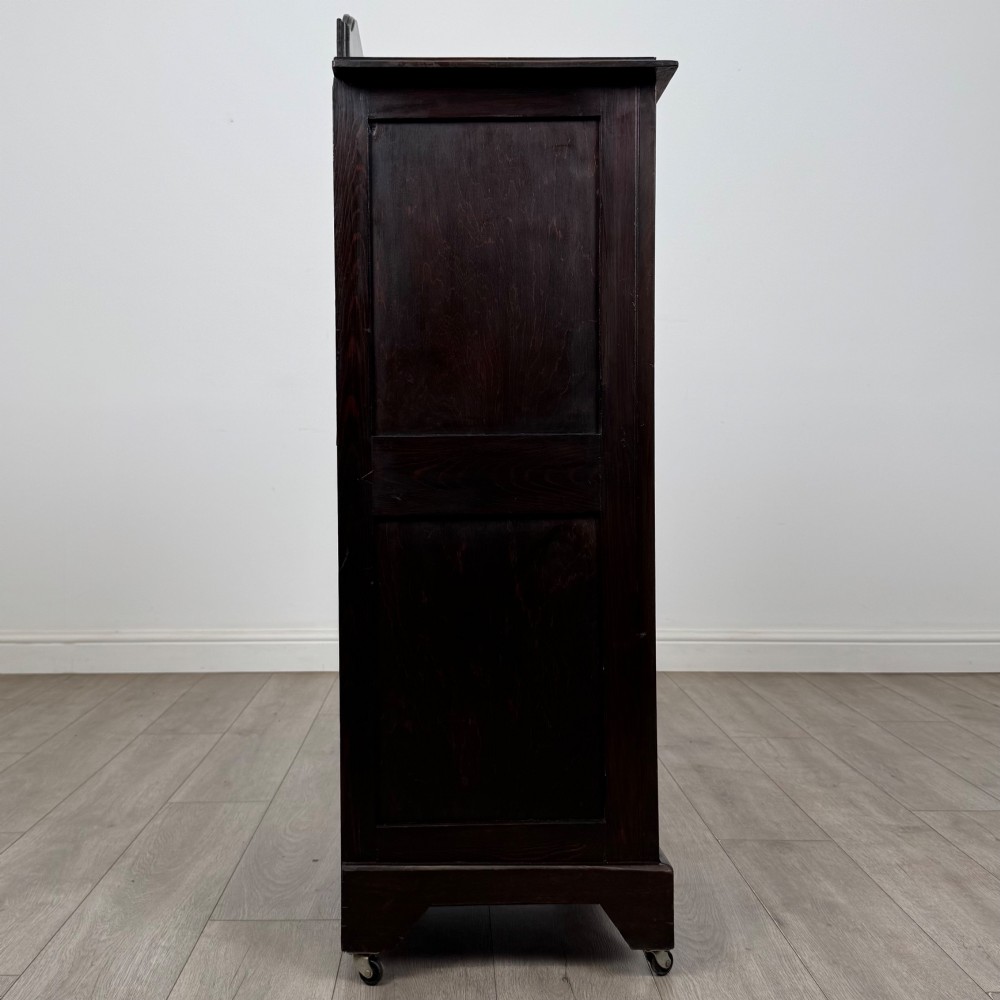 A tall, dark mahogany Edwardian chest features four stacked drawers above a single carved cupboard door, set on small brass castors. View VIII