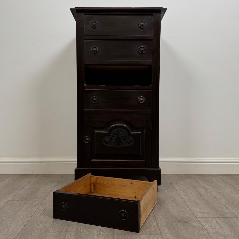 A tall, dark mahogany Edwardian chest features four stacked drawers above a single carved cupboard door, set on small brass castors. View XI