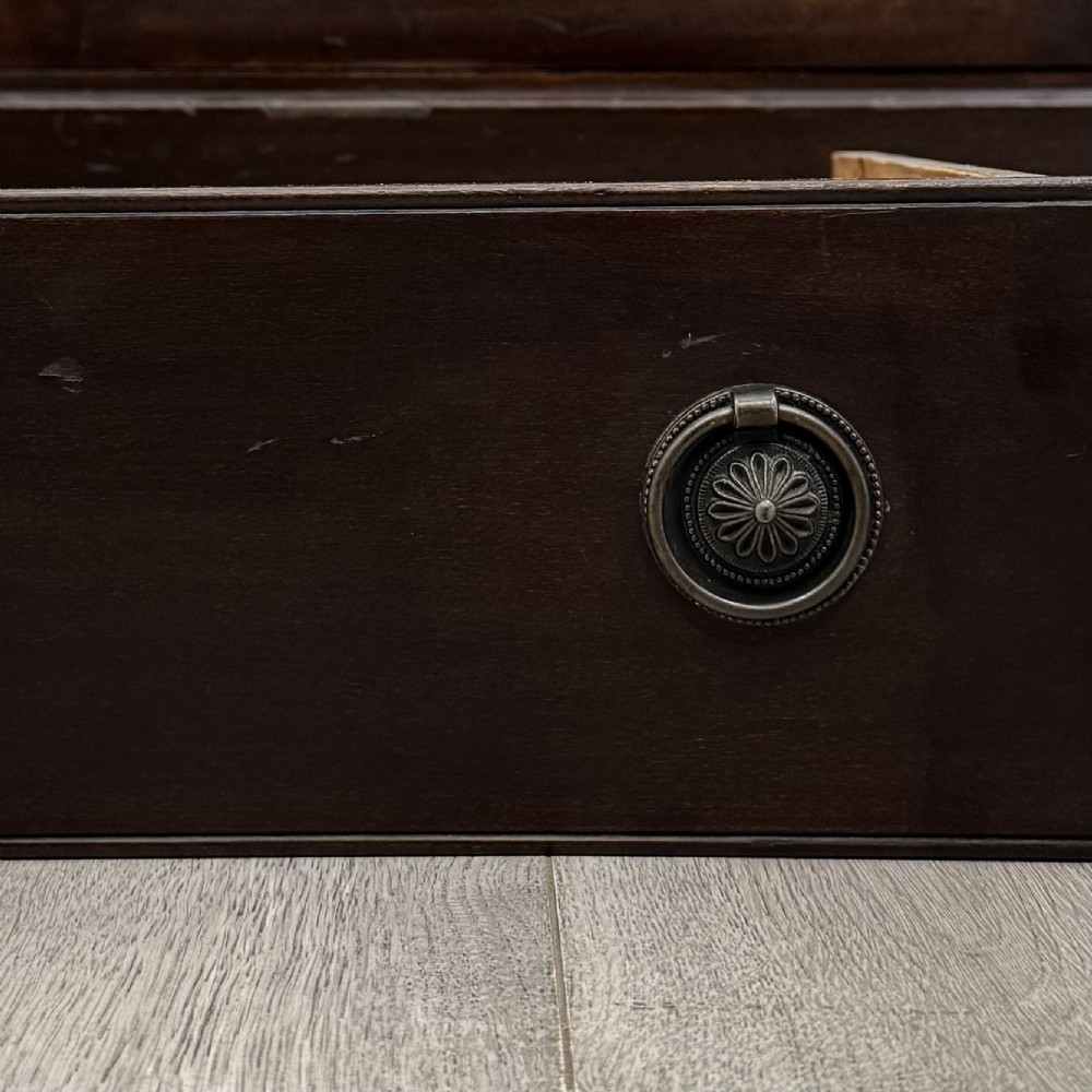 A tall, dark mahogany Edwardian chest features four stacked drawers above a single carved cupboard door, set on small brass castors. View XII