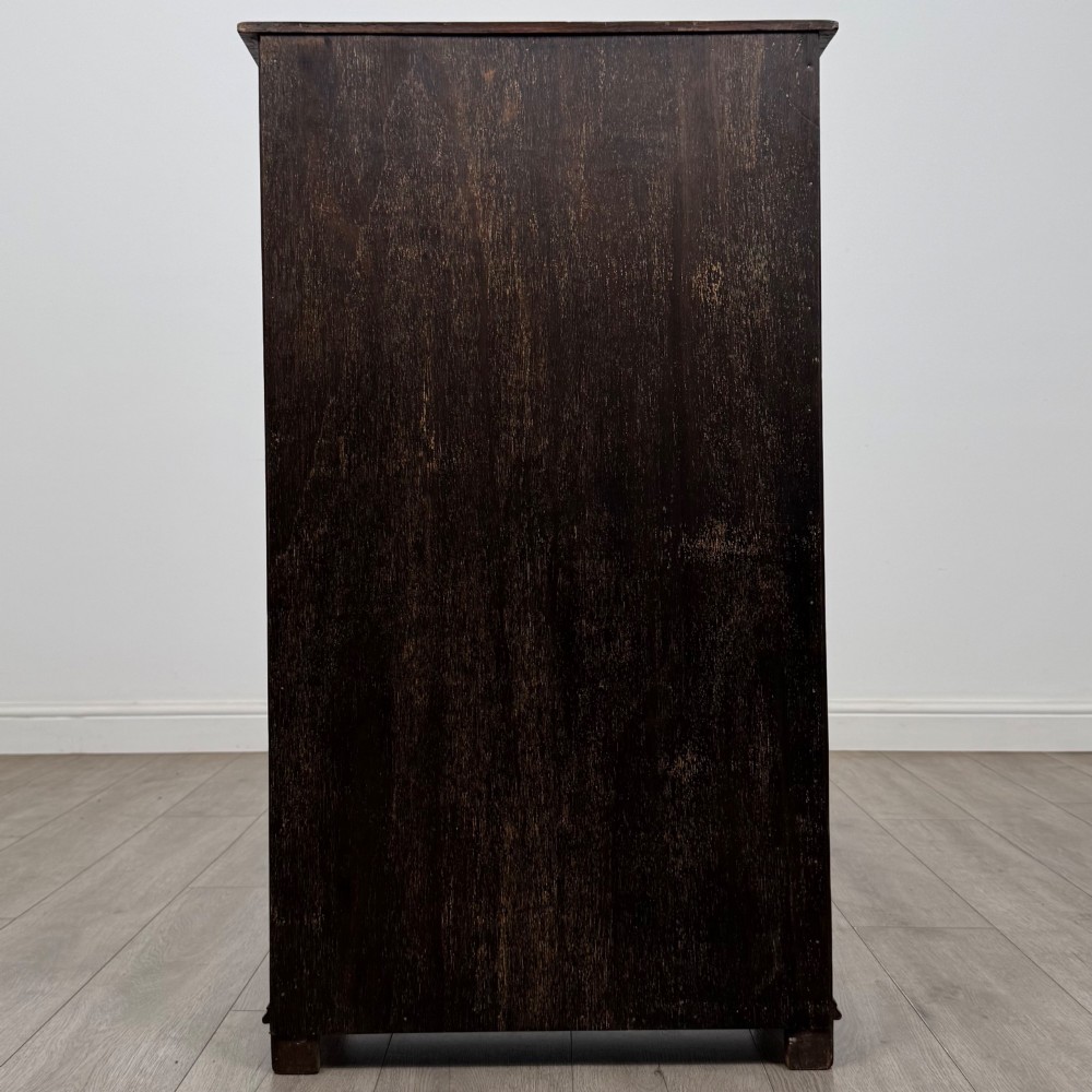 A dark oak open bookcase featuring a carved top frieze, three open display shelves, and a single bottom drawer with a central wooden knob handle. View VI