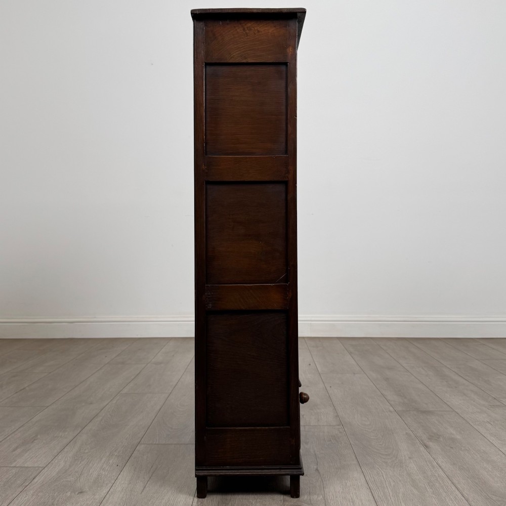 A dark oak open bookcase featuring a carved top frieze, three open display shelves, and a single bottom drawer with a central wooden knob handle. View VIII