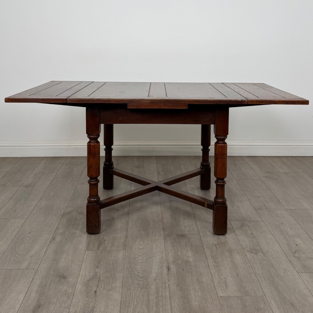 An Edwardian oak draw-leaf dining table featuring turned legs, a rectangular plank top, and an X-shaped cross stretcher base. View II
