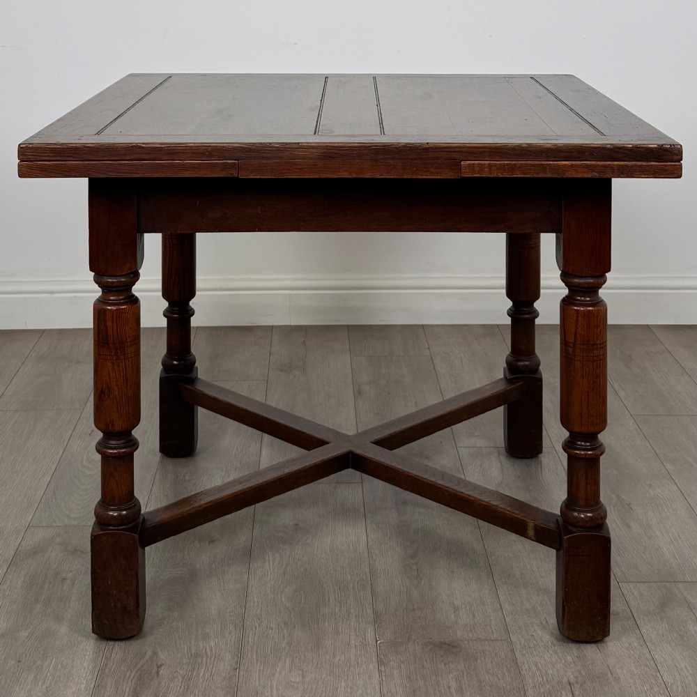 An Edwardian oak draw-leaf dining table featuring turned legs, a rectangular plank top, and an X-shaped cross stretcher base. View III