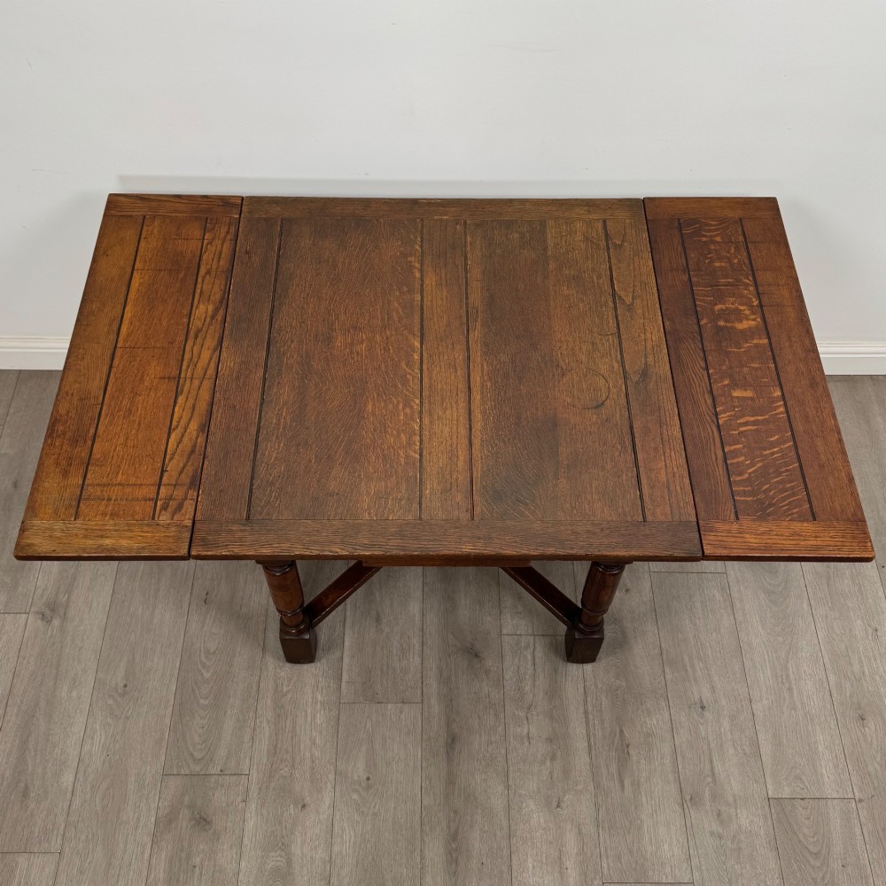 An Edwardian oak draw-leaf dining table featuring turned legs, a rectangular plank top, and an X-shaped cross stretcher base. View V