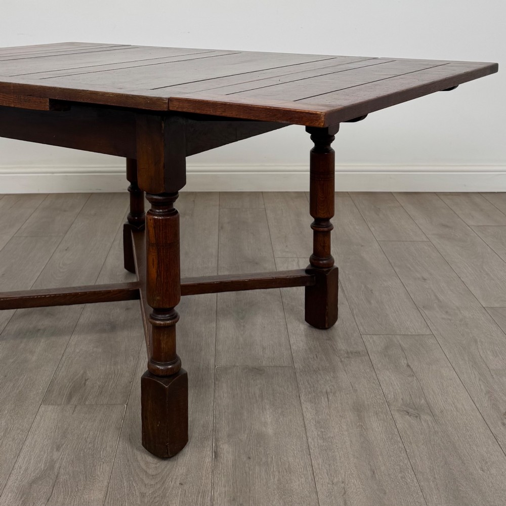 An Edwardian oak draw-leaf dining table featuring turned legs, a rectangular plank top, and an X-shaped cross stretcher base. View VI