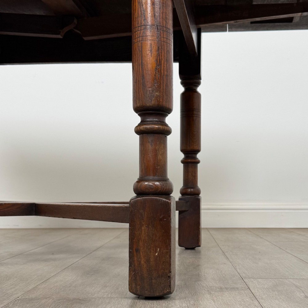 An Edwardian oak draw-leaf dining table featuring turned legs, a rectangular plank top, and an X-shaped cross stretcher base. View VII