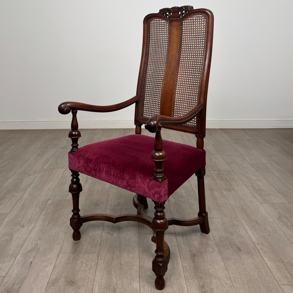 A set of twelve mahogany dining chairs featuring high cane-back panels, carved cresting rails, turned legs, and deep red velvet upholstered seats. View II