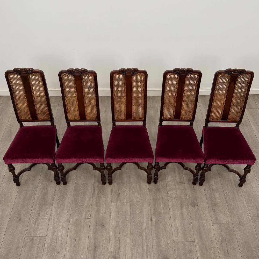 A set of twelve mahogany dining chairs featuring high cane-back panels, carved cresting rails, turned legs, and deep red velvet upholstered seats. View VIII