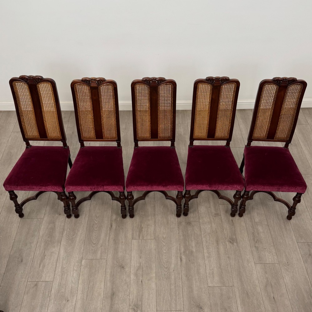 A set of twelve mahogany dining chairs featuring high cane-back panels, carved cresting rails, turned legs, and deep red velvet upholstered seats. View IX