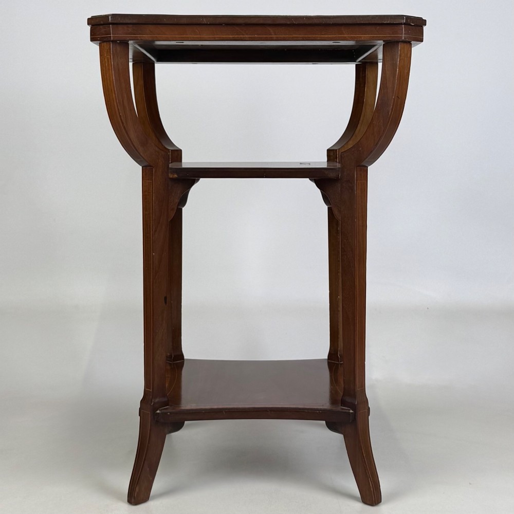 An Edwardian dark mahogany side table featuring a square top, sweeping curved leg supports, and two lower shelves. View IV