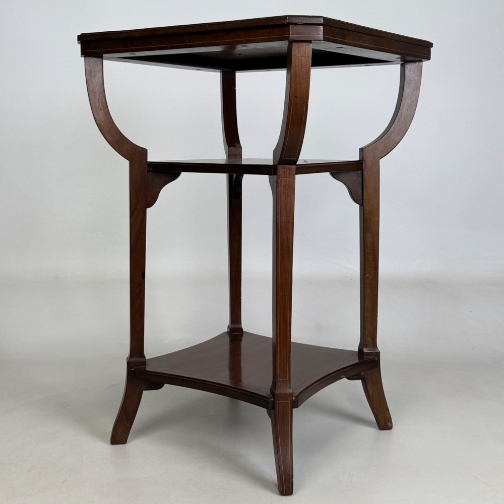 An Edwardian dark mahogany side table featuring a square top, sweeping curved leg supports, and two lower shelves. View V