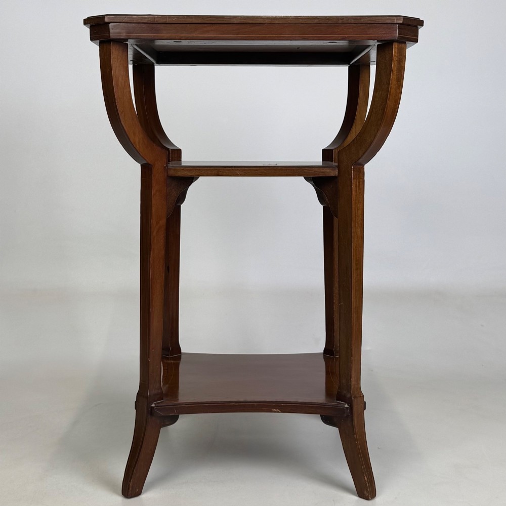 An Edwardian dark mahogany side table featuring a square top, sweeping curved leg supports, and two lower shelves. View VI