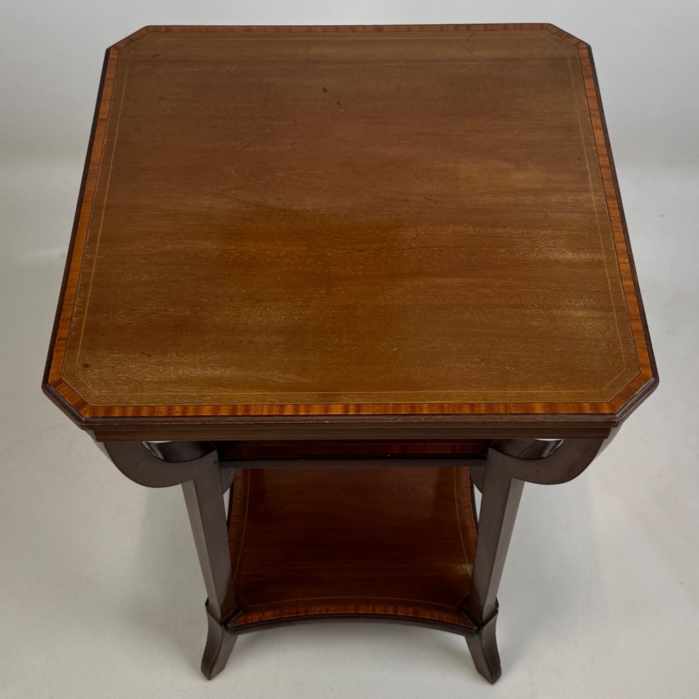 An Edwardian dark mahogany side table featuring a square top, sweeping curved leg supports, and two lower shelves. View VII
