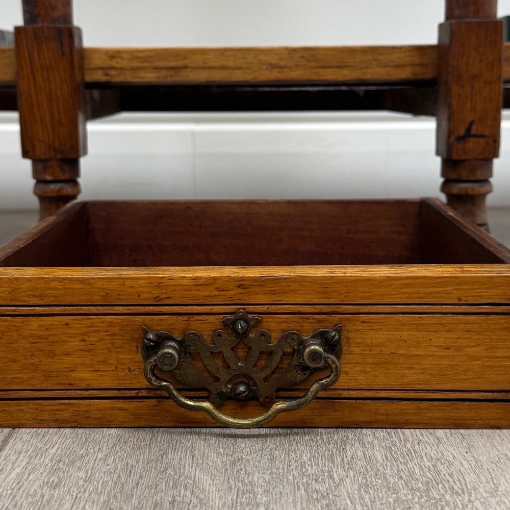 An Edwardian golden oak hall stand with a top spindle gallery, central glove drawer with brass handle, twin umbrella rail apertures, and metal drip trays on the lower shelf. View XI