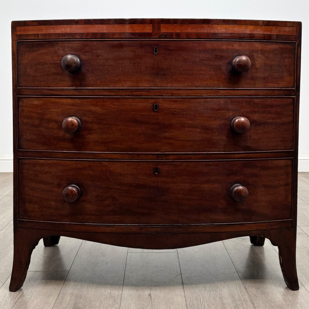 An 18th-century mahogany bow-front chest of drawers featuring three graduated drawers with turned wooden handles and splayed feet.