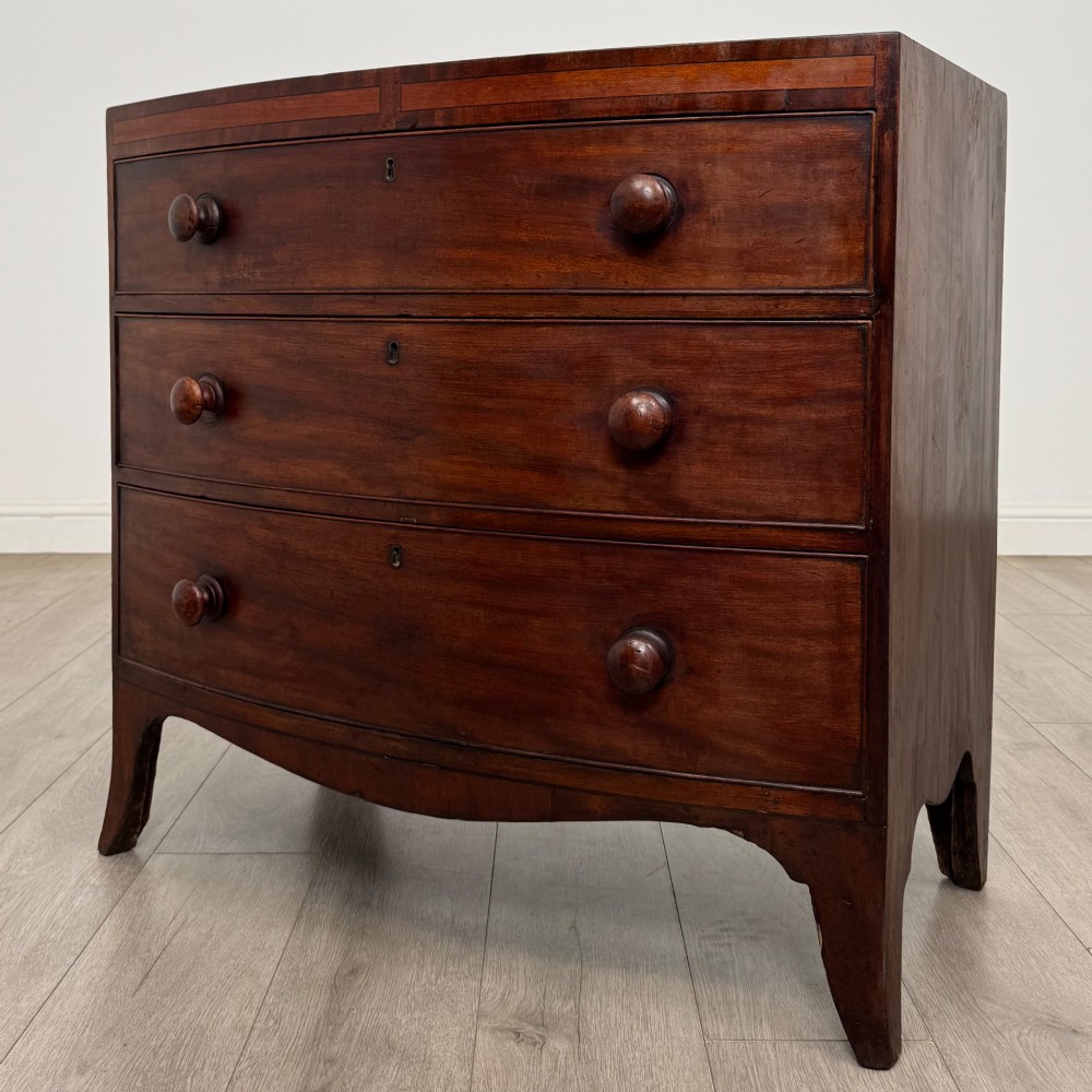 An 18th-century mahogany bow-front chest of drawers featuring three graduated drawers with turned wooden handles and splayed feet. View II
