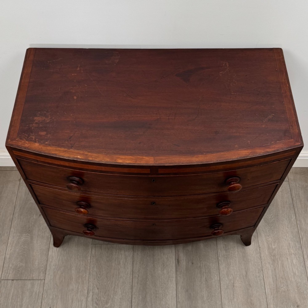 An 18th-century mahogany bow-front chest of drawers featuring three graduated drawers with turned wooden handles and splayed feet. View IX