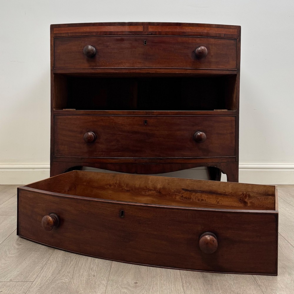 An 18th-century mahogany bow-front chest of drawers featuring three graduated drawers with turned wooden handles and splayed feet. View X