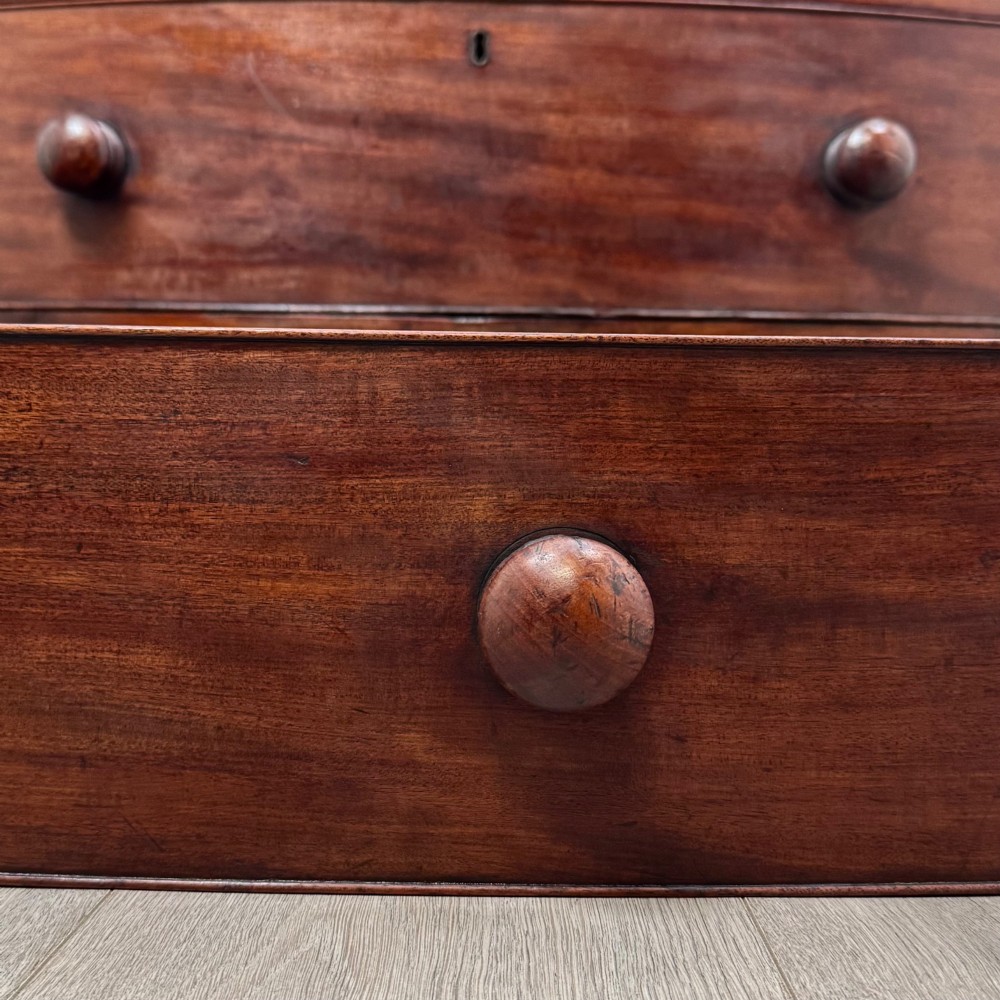 An 18th-century mahogany bow-front chest of drawers featuring three graduated drawers with turned wooden handles and splayed feet. View XI