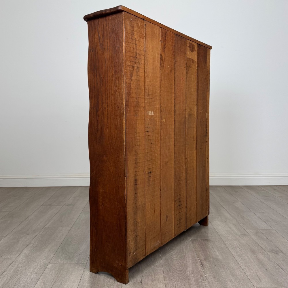 An early 20th-century medium brown solid oak open bookcase featuring four fixed shelves and a planked back panel. View IV