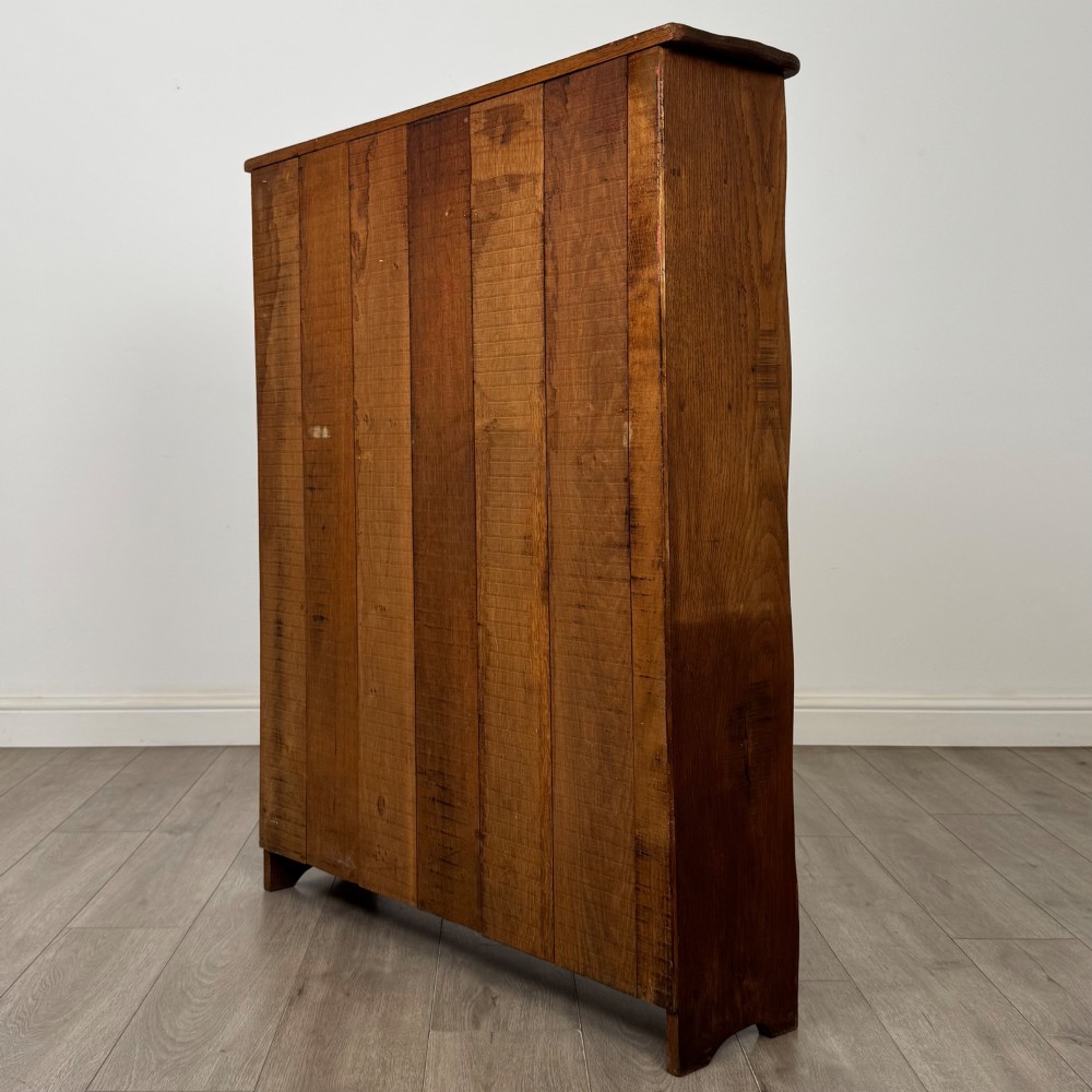 An early 20th-century medium brown solid oak open bookcase featuring four fixed shelves and a planked back panel. View VI