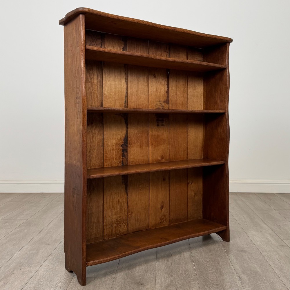 An early 20th-century medium brown solid oak open bookcase featuring four fixed shelves and a planked back panel. View VIII