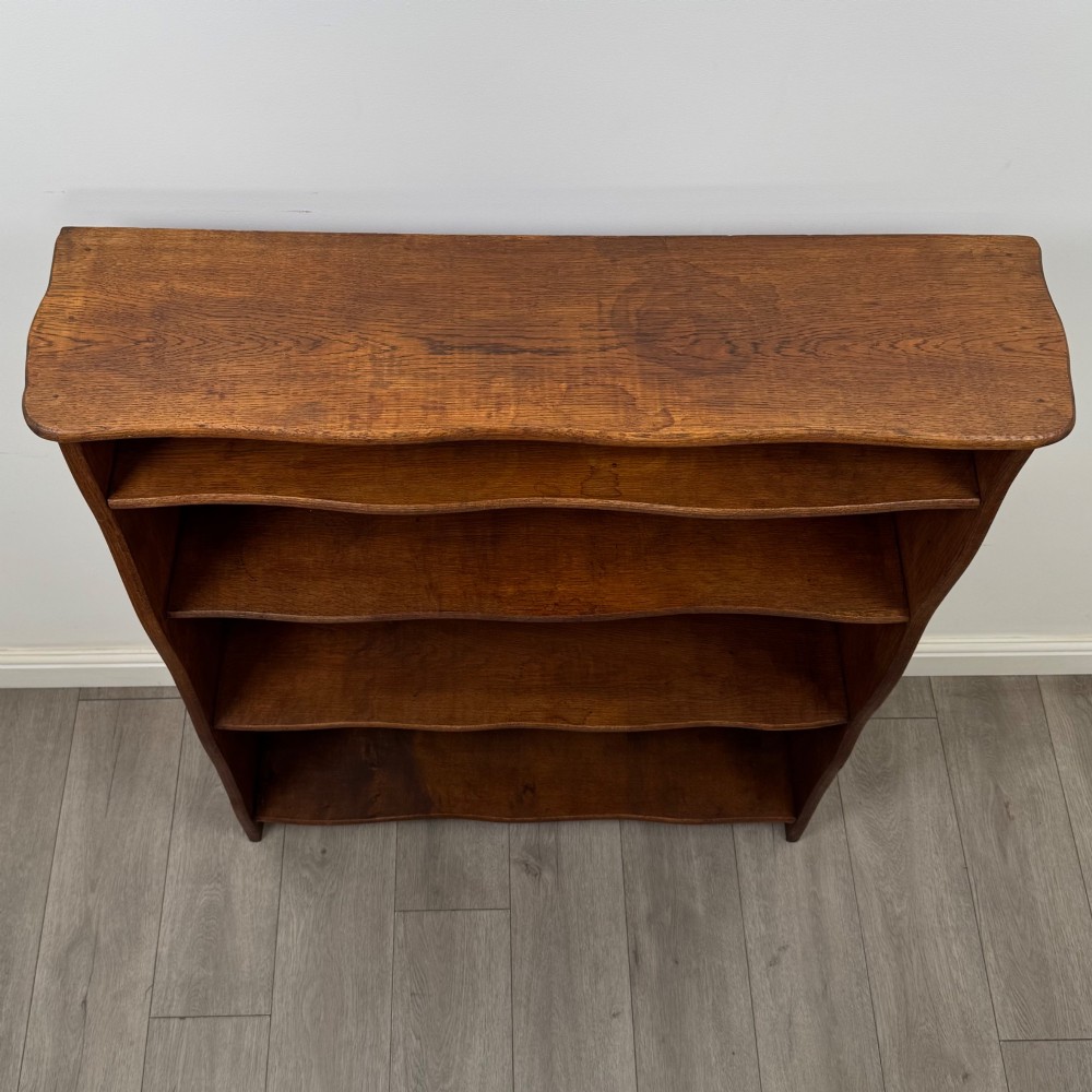 An early 20th-century medium brown solid oak open bookcase featuring four fixed shelves and a planked back panel. View IX