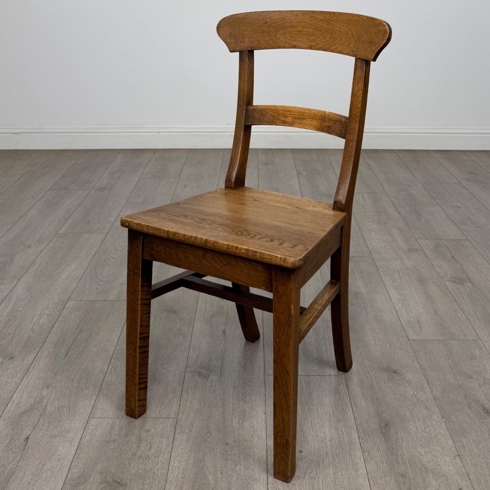 A set of six Victorian solid oak dining chairs featuring curved backrails, solid wooden seats, and square legs with stretchers. View II