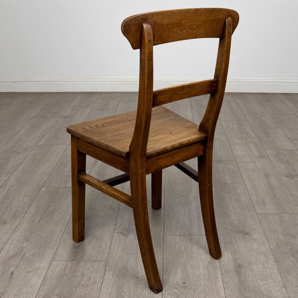 A set of six Victorian solid oak dining chairs featuring curved backrails, solid wooden seats, and square legs with stretchers. View III