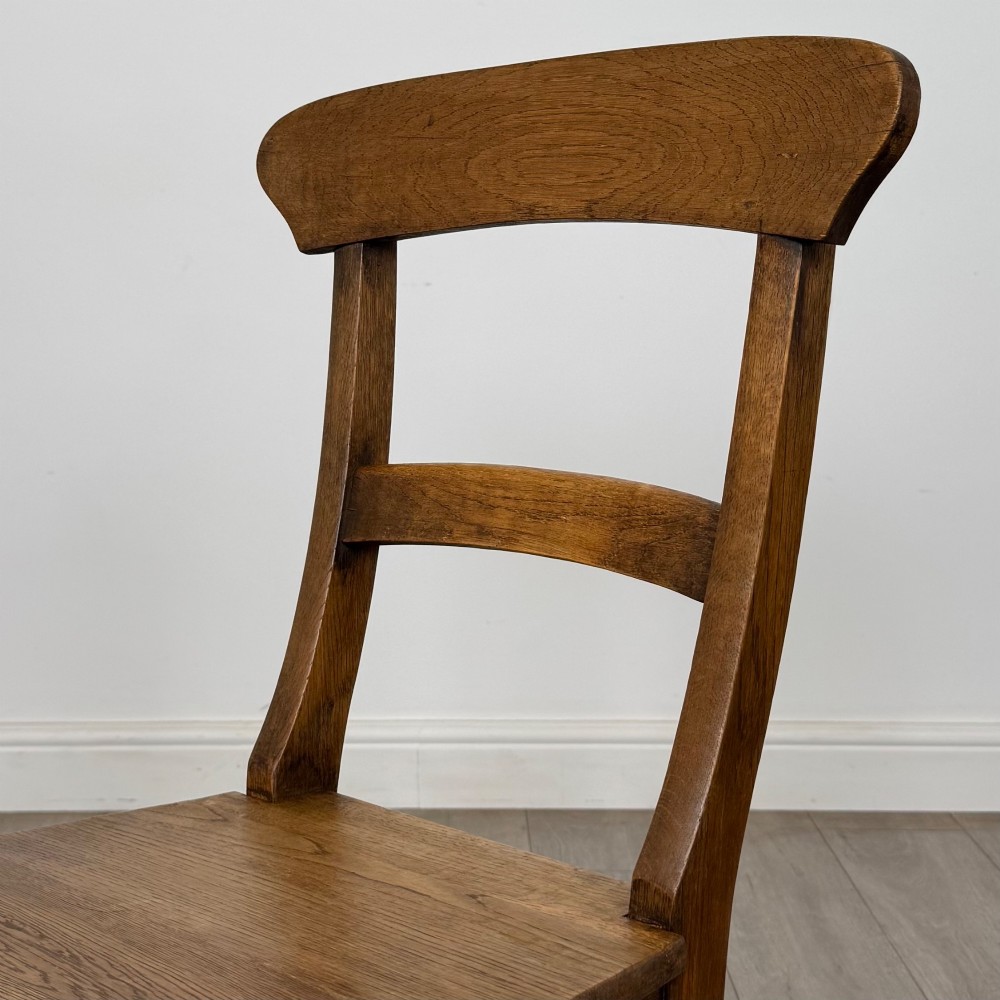 A set of six Victorian solid oak dining chairs featuring curved backrails, solid wooden seats, and square legs with stretchers. View IV