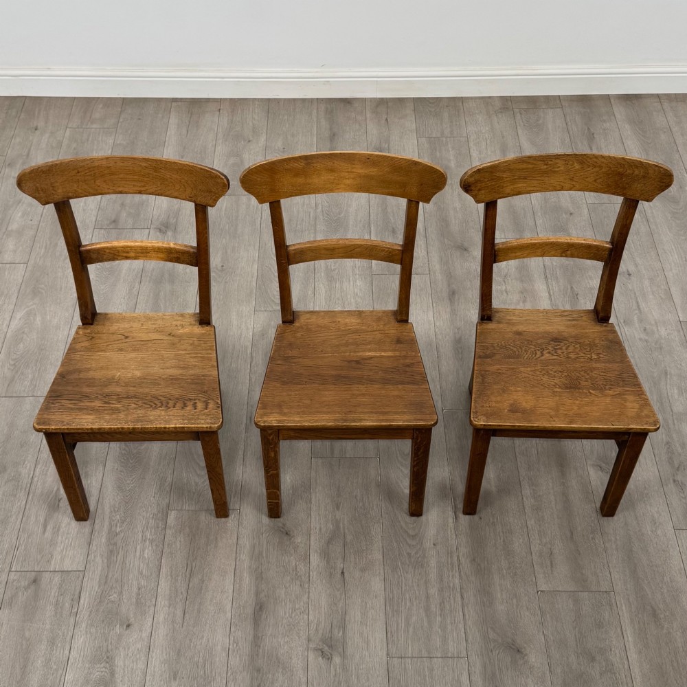 A set of six Victorian solid oak dining chairs featuring curved backrails, solid wooden seats, and square legs with stretchers. View VII