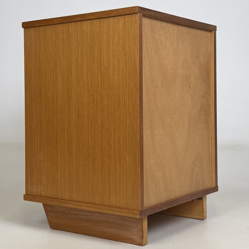 A pair of mid-century modern warm brown teak bedside cabinets featuring open upper shelf cubbies, lower cupboard doors with dark round wooden knobs, and low angled feet. View VI