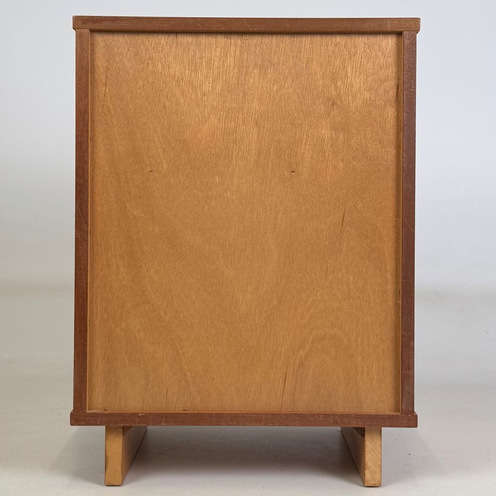 A pair of mid-century modern warm brown teak bedside cabinets featuring open upper shelf cubbies, lower cupboard doors with dark round wooden knobs, and low angled feet. View VII