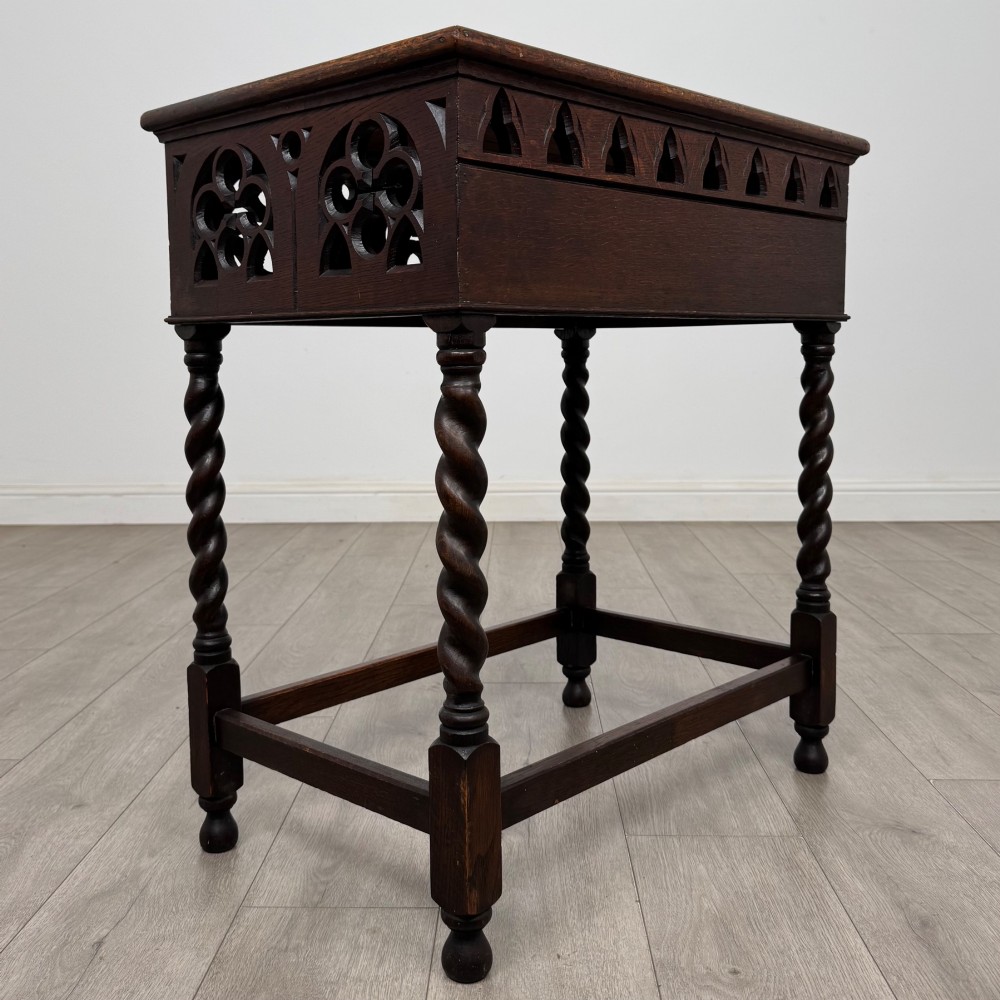 A dark oak Gothic style side table featuring three pierced tracery carved panels on the apron and four barley twist legs connected by box stretchers. View IV