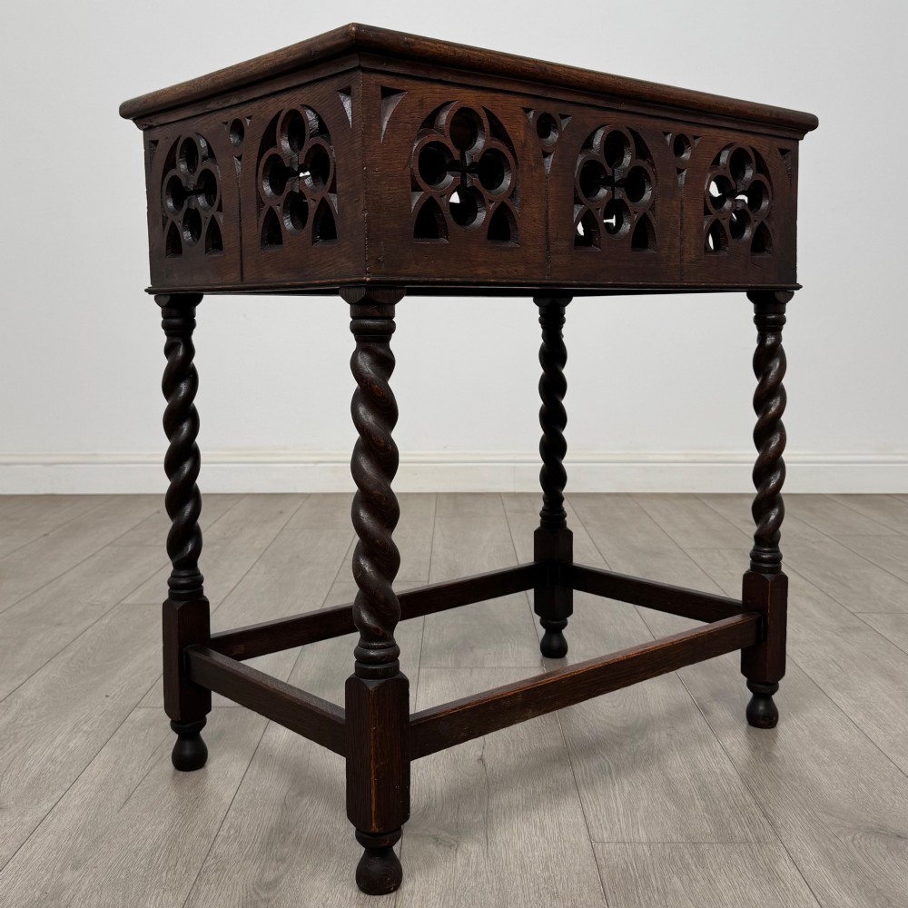 A dark oak Gothic style side table featuring three pierced tracery carved panels on the apron and four barley twist legs connected by box stretchers. View VIII