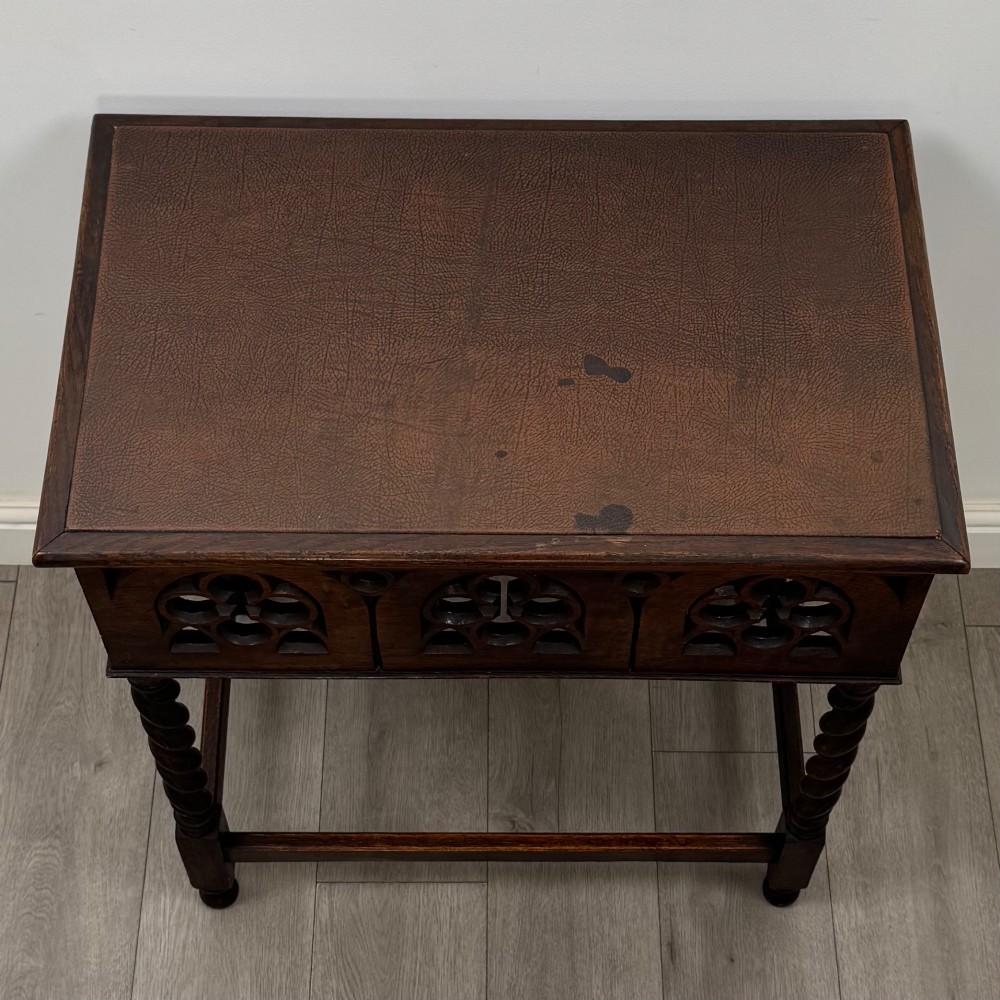 A dark oak Gothic style side table featuring three pierced tracery carved panels on the apron and four barley twist legs connected by box stretchers. View IX