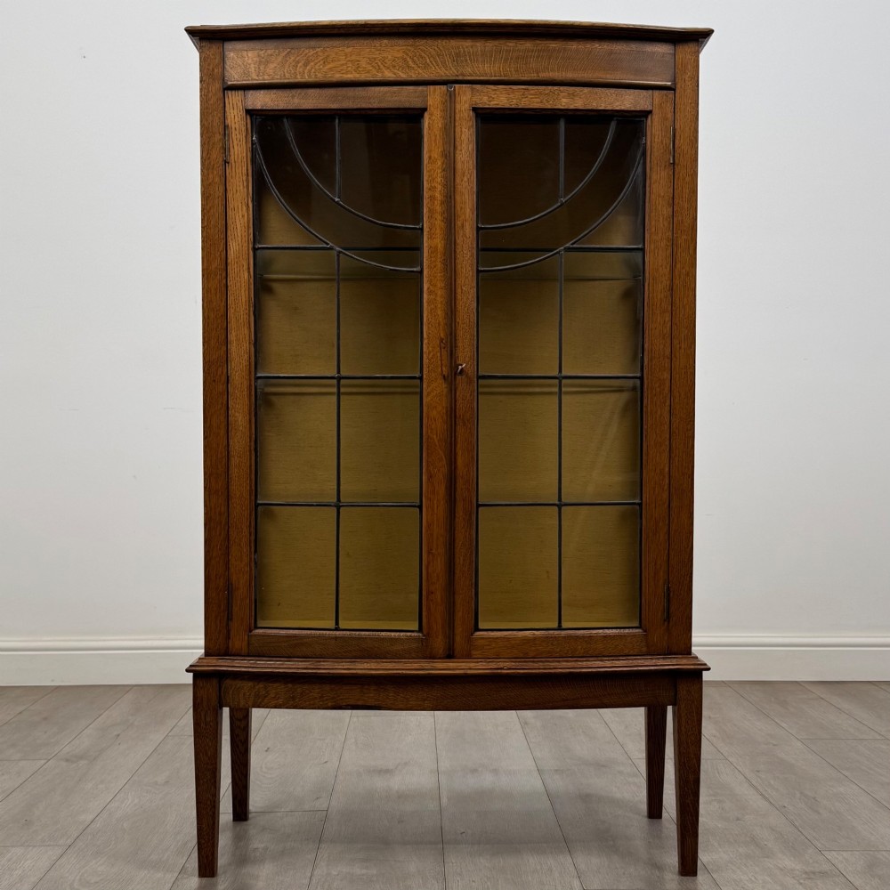 An Edwardian oak display cabinet with double leaded glass doors and square tapered legs.