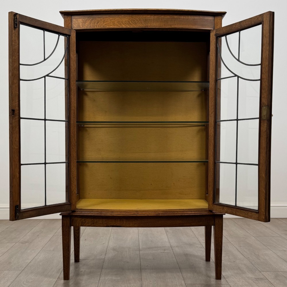 An Edwardian oak display cabinet with double leaded glass doors and square tapered legs. View II